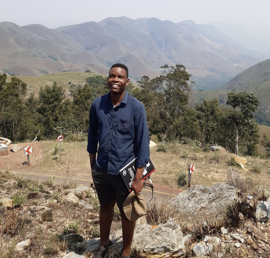 Floyd Mautle smiling outdoors in mountainous terrain during fieldwork